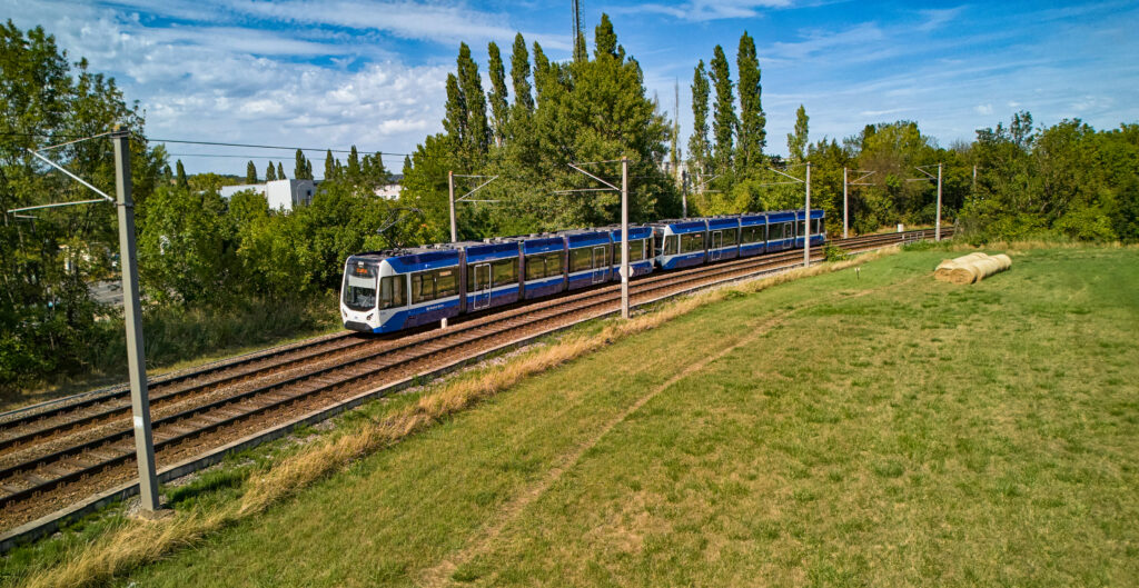 TW500 Zug der Badner Bahn fährt auf der Strecke im Spätsommer