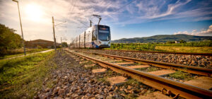 TW500 der Badner Bahn fährt entlang der Strecke in spätsommerlicher Landschaft